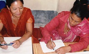 Two women writing on paper, learning about mental health